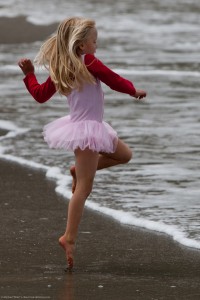 Cute Little Girl in Pink Dances on the Beach during the Kite Fes